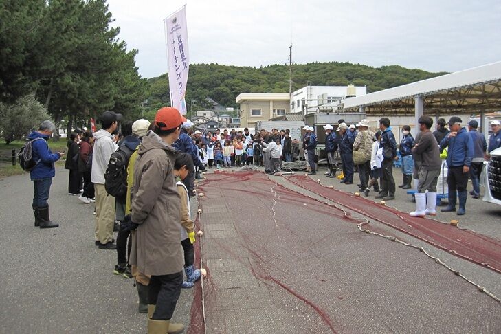 Participants receiving an explanation from Fisheries Cooperative members about the seine net