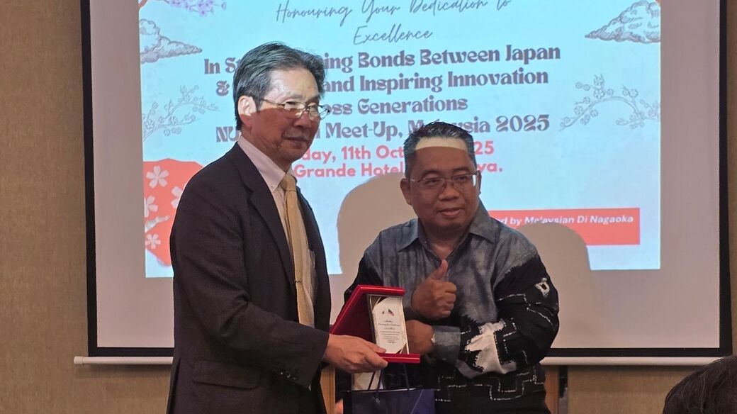 鎌土学長とアルバイン氏が感謝の気持ちを込めて記念品を交換